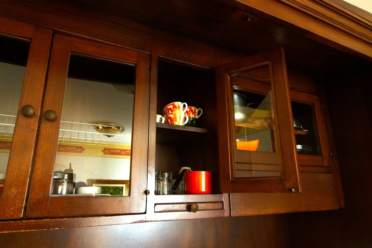Cozy kitchen with dark wood and neatly arranged shelves featuring colorful mugs.