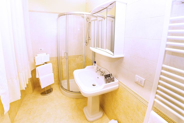 A simple and bright bathroom featuring a shower, sink, and mirror in a neat environment.