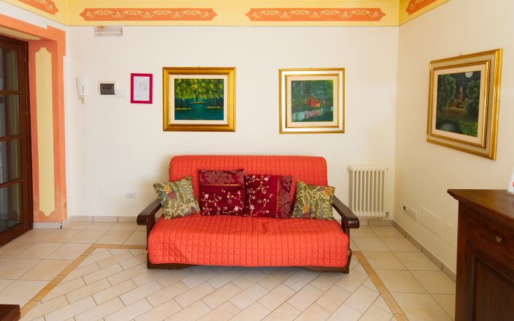 Warm living room with an orange sofa and simple wall decorations.
