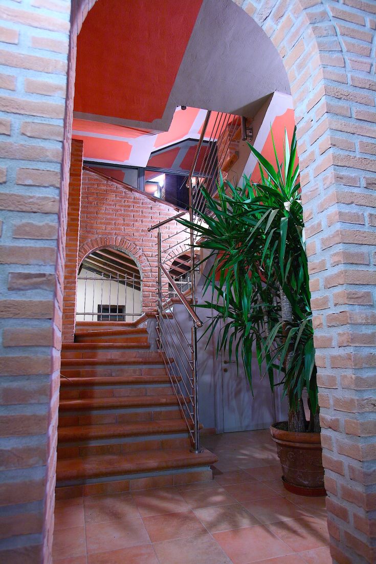 Interior of a vacation home showing a staircase, potted plants, and exposed brick walls.