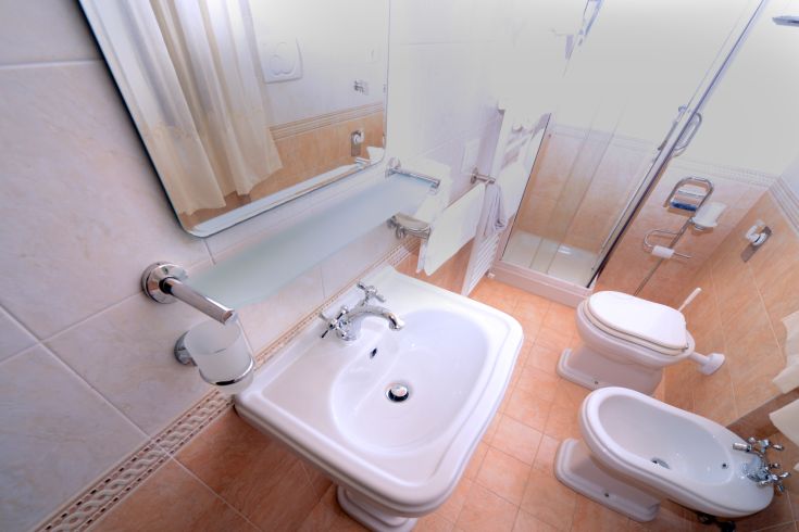 Essential bathroom with a sink, shower, and toilet inside an apartment.
