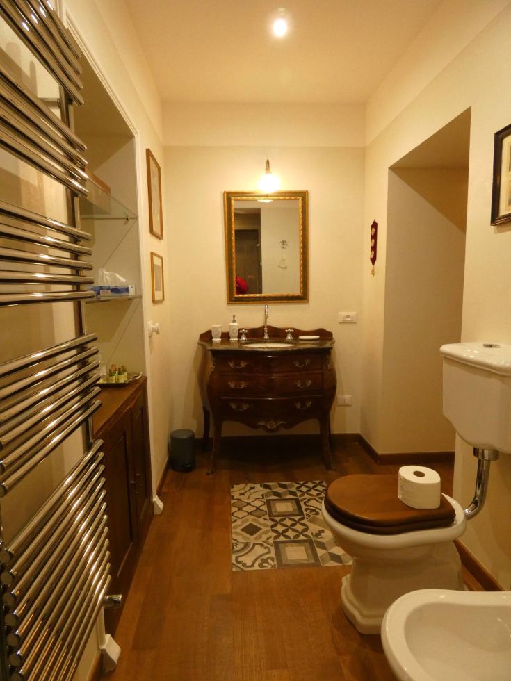 Bagno semplice con finiture in legno, uno specchio e pavimento arricchito.