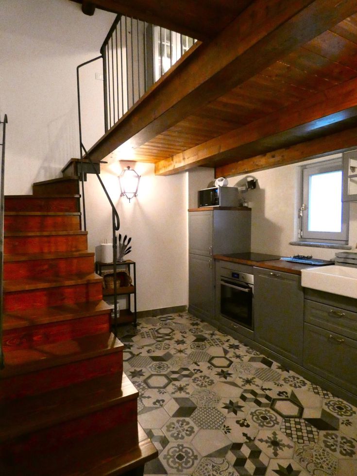 Cucina ristrutturata in un appartamento, con mobili funzionali, scala in legno e piastrelle decorative.