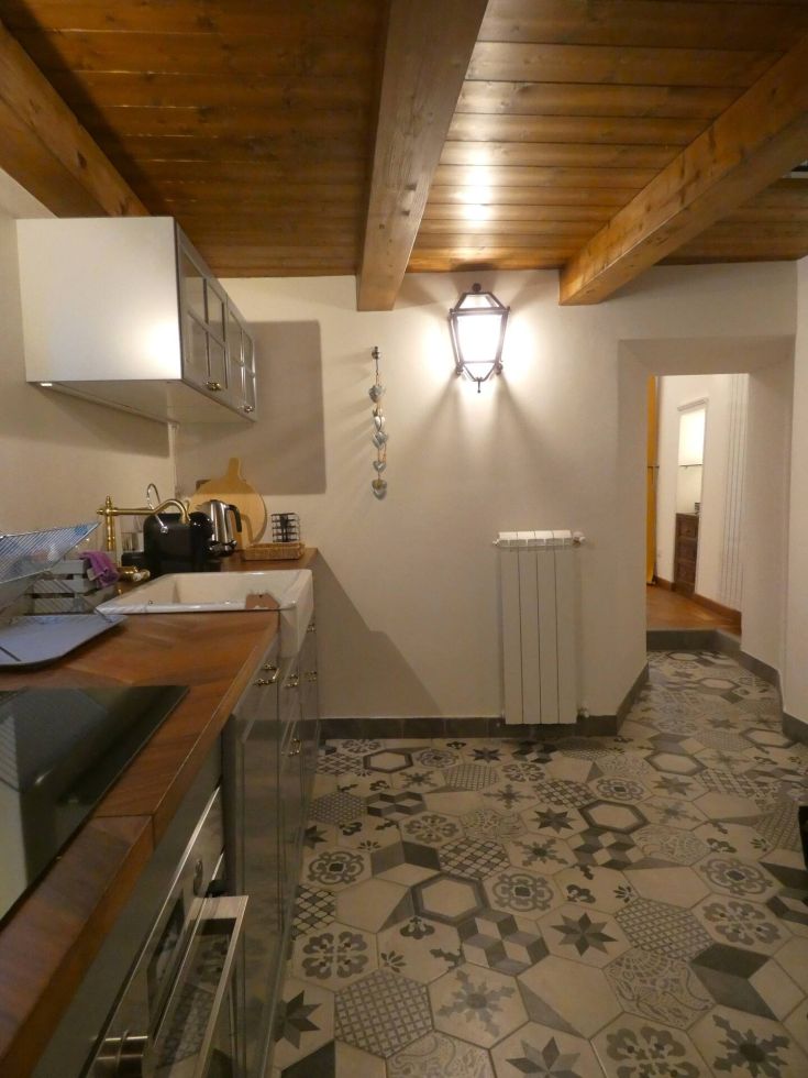 Cucina calda e ariosa con elementi moderni e pavimenti decorativi. Ideale per creare momenti in compagnia.