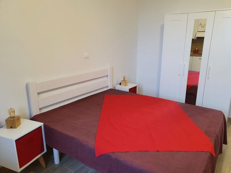 Ein einfaches Schlafzimmer mit einem Doppelbett und zeitgemäßer, funktioneller Einrichtung.