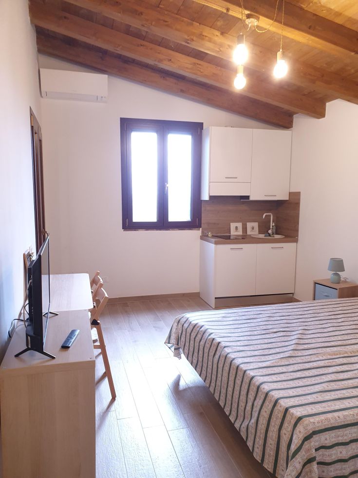 Kleines Apartment mit Bett, Kochnische und Holzverkleidungen.