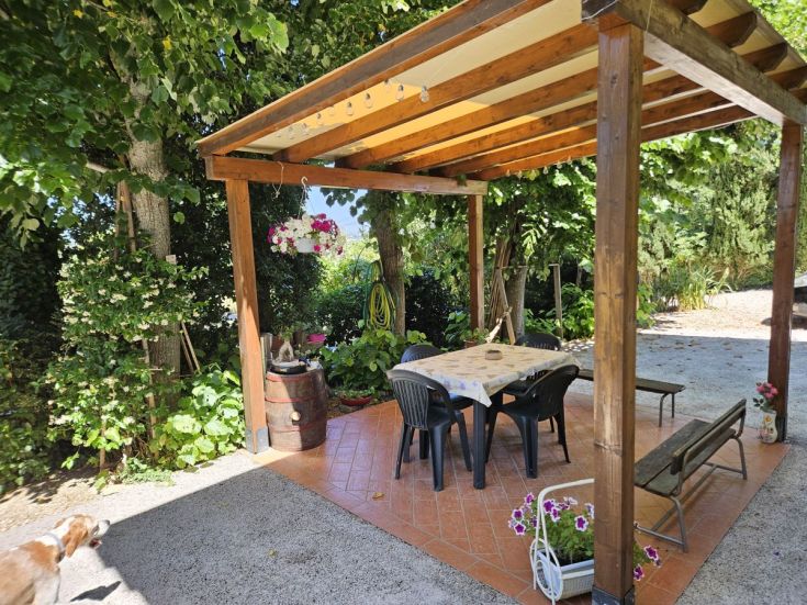 Eine kleine Außenecke mit einem Tisch und Stühlen, umgeben von üppigem Grün und blühenden Pflanzen.