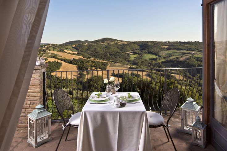Un ambiente accogliente con un tavolo apparecchiato, affacciato su dolci colline umbre.