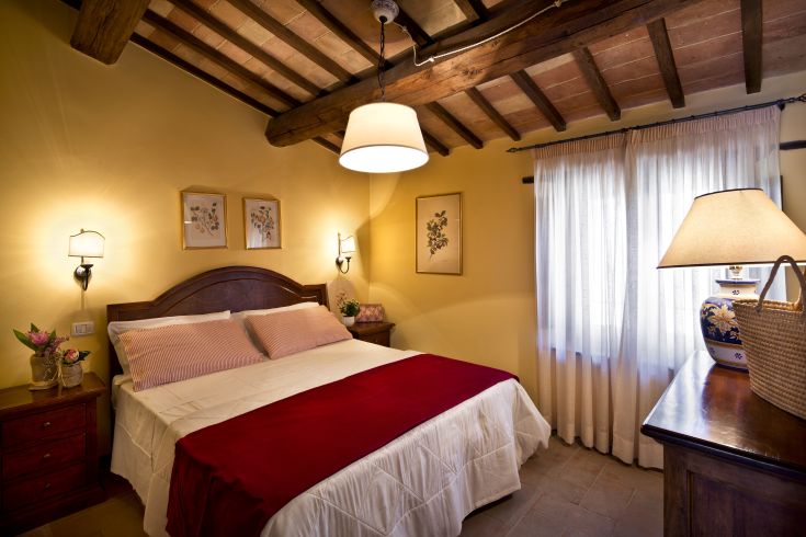 Camera confortevole con letto matrimoniale, arredi in legno e semplici decorazioni floreali.