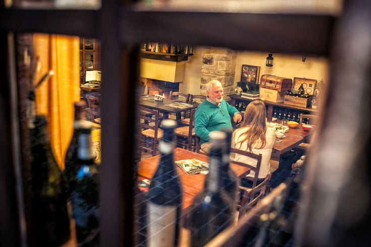 Un incontro piacevole in un ristorante, con un'atmosfera calda e accogliente, caratterizzata da dettagli rustici e un clima conviviale.