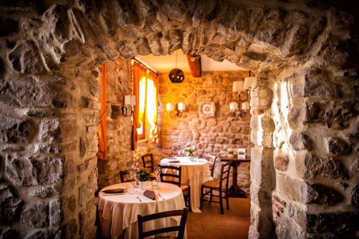 Ambiente intimo caratterizzato da archi in pietra e tavoli ben preparati.