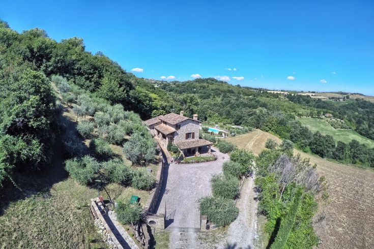 Ein Steinhof umgeben von Olivenhainen, mit Blick auf das Tal und Platz für Spaziergänge und Entspannung.