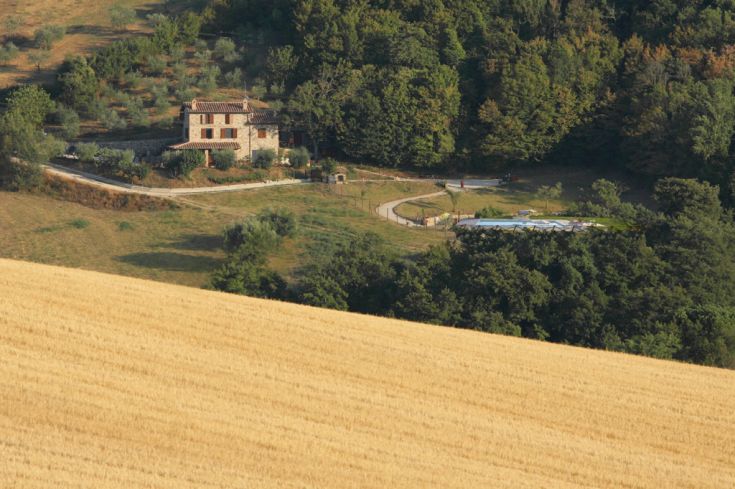 Ein historisches Gebäude auf einem Hügel, umgeben von Olivenhainen und der ländlichen Landschaft Umbriens.