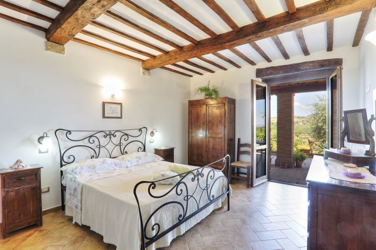 Gemütliches Schlafzimmer mit Blick auf eine Naturlandschaft, einfache Einrichtung und Holzelemente.