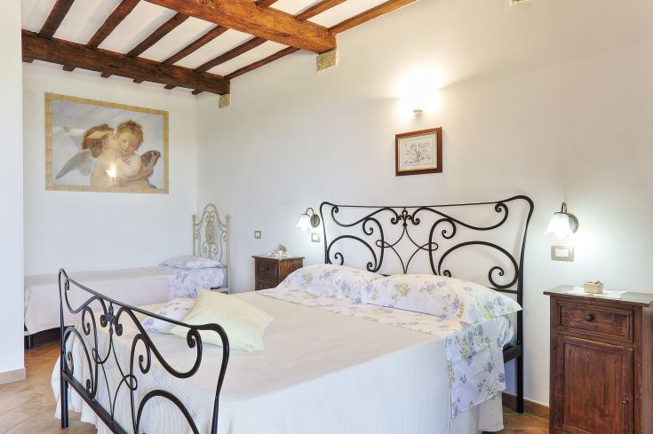 Einfaches Zimmer mit bequemen Betten, dekoriert mit einem Gemälde und umgeben von Grün.