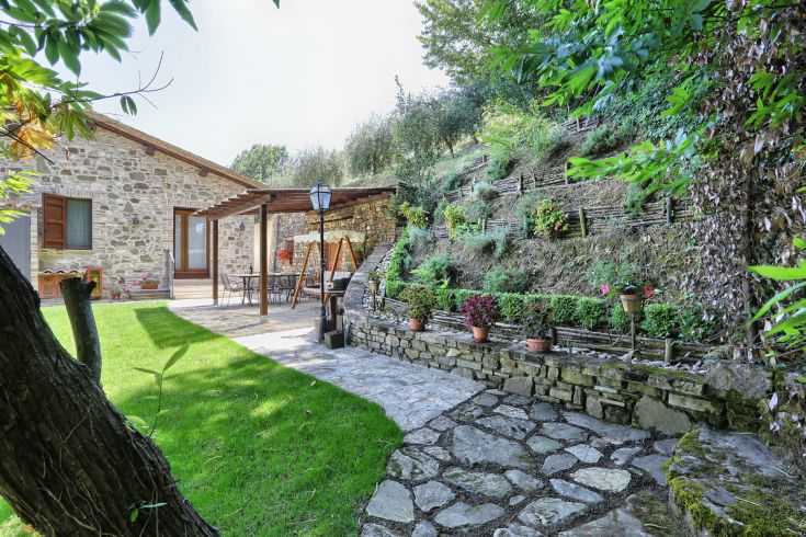 Eine entspannende Ecke, umgeben von Natur, mit einem Steingebäude und einem gepflegten Garten, ideal für die Zeit im Freien.