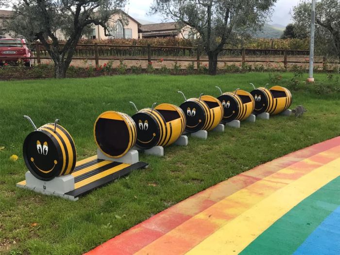 giardino con botti tagliate e colorate ad ape, con strisce 