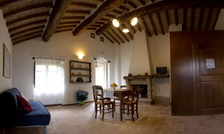 Ein Wohnzimmer mit freiliegenden Balken und schlichten Möbeln. Ein warmer Raum für gemütliche Momente.