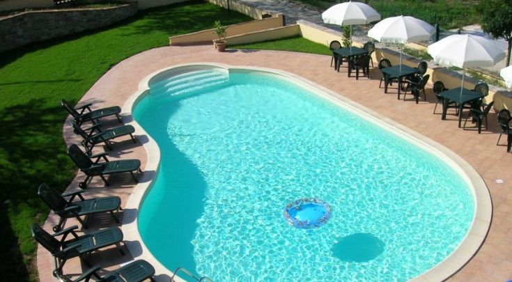Une piscine paisible entourée de chaises longues et de parasols pour se détendre.