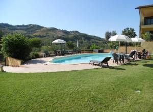 Une piscine située dans un jardin bien entretenu, entourée de verdure avec une vue sur les collines environnantes.
