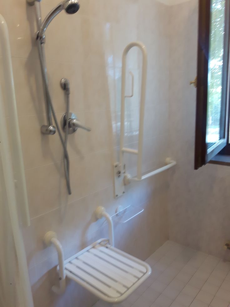 Douche confortable avec barre de soutien et siège pour un usage pratique et facile.