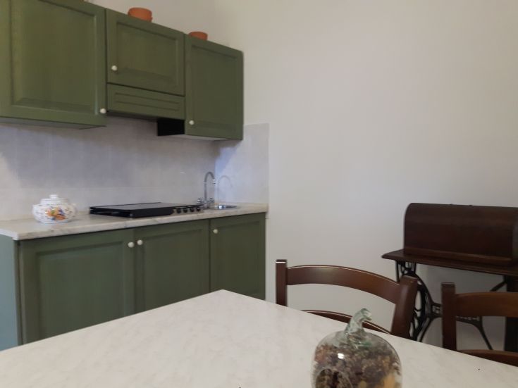 Une cuisine simple et fonctionnelle avec des armoires vertes et un plan de travail en marbre, idéale pour préparer divers plats.