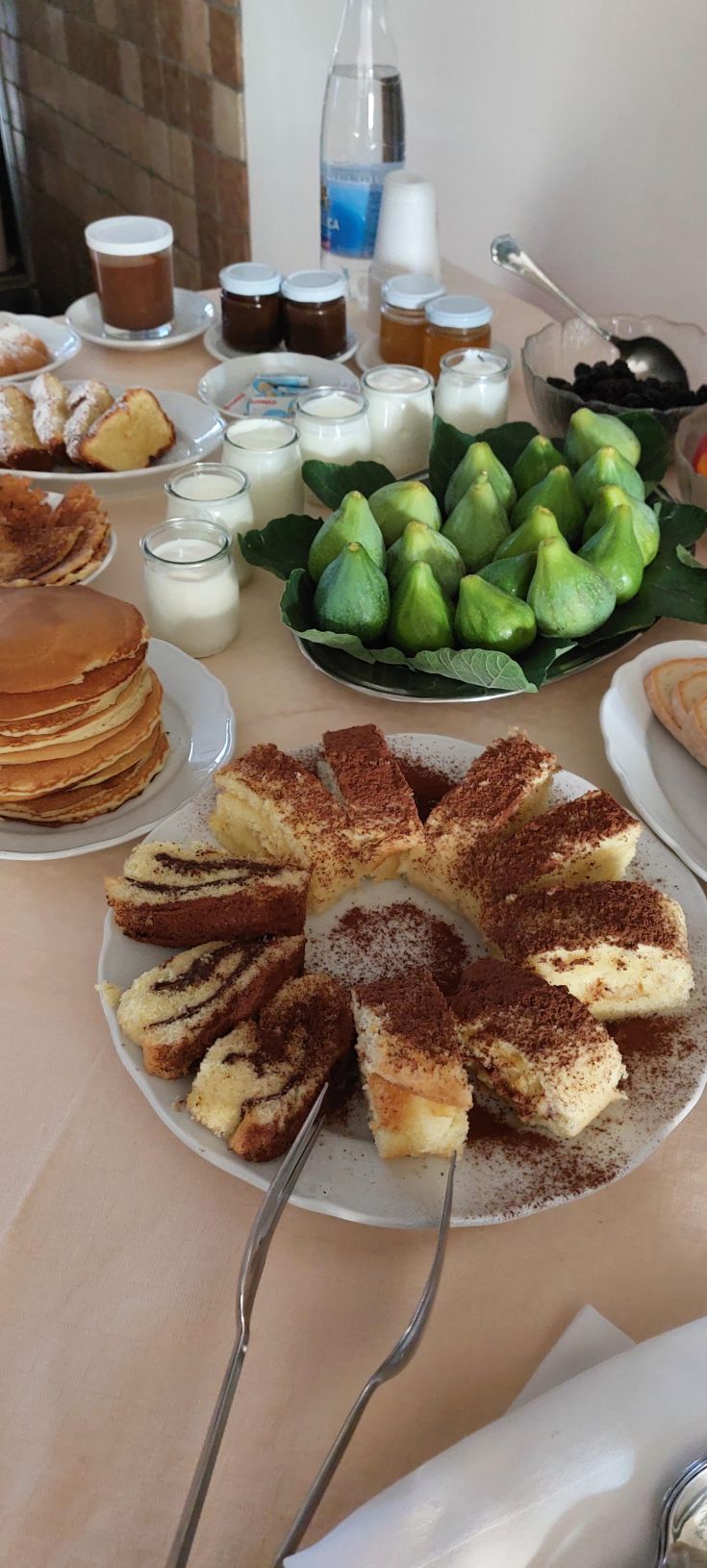 Un buffet varié avec des douceurs, des pancakes et du yaourt accompagnés de fruits frais.