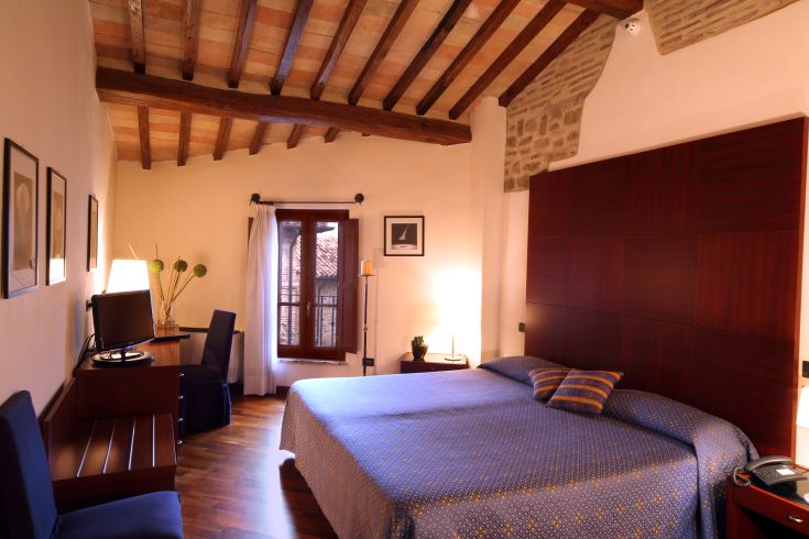 Chambre confortable avec plafond à poutres en bois et vue sur un paysage paisible.