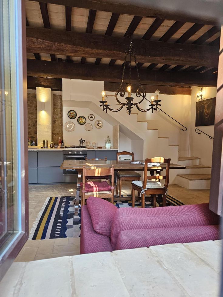 Cucina-soggiorno moderno con tavolo vintage e area relax, spazio ben illuminato e confortevole.