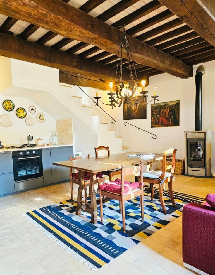 Cucina e soggiorno arredati in modo semplice, con tavolo da pranzo e stufa, in un ampio edificio tipico.