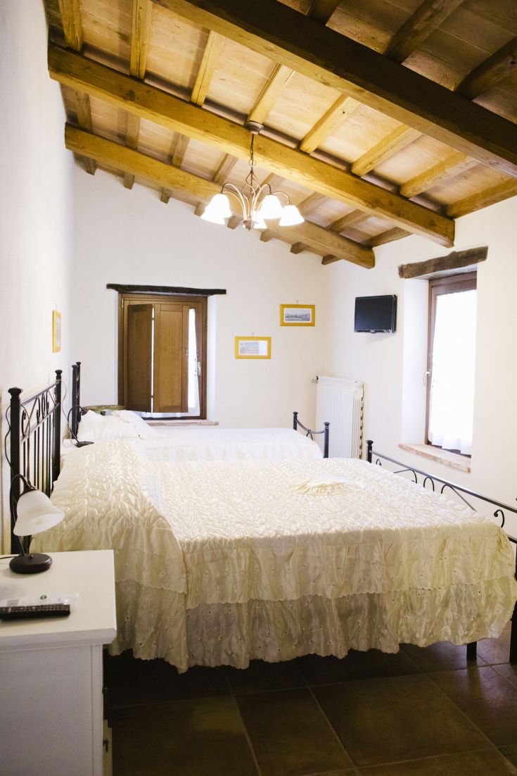 Camera accogliente con letti matrimoniali e travi in legno a vista sul soffitto.