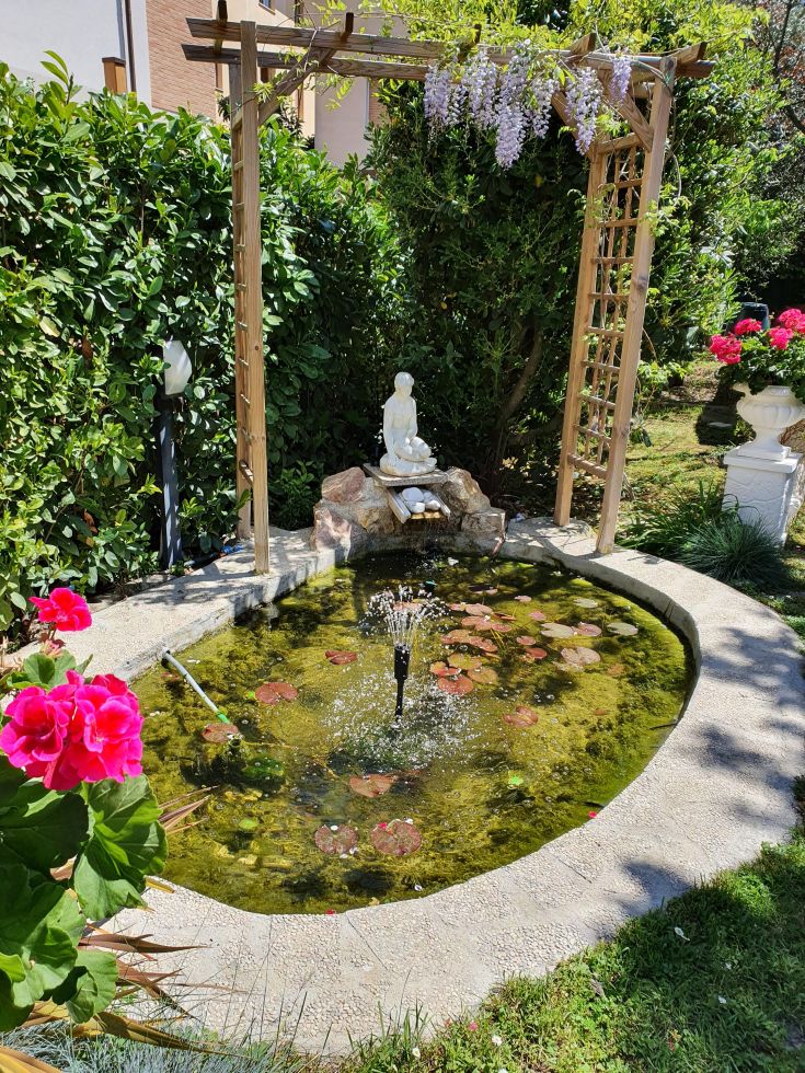 A serene garden with a central fountain, decorated statues, and various flowers, ideal for relaxation.