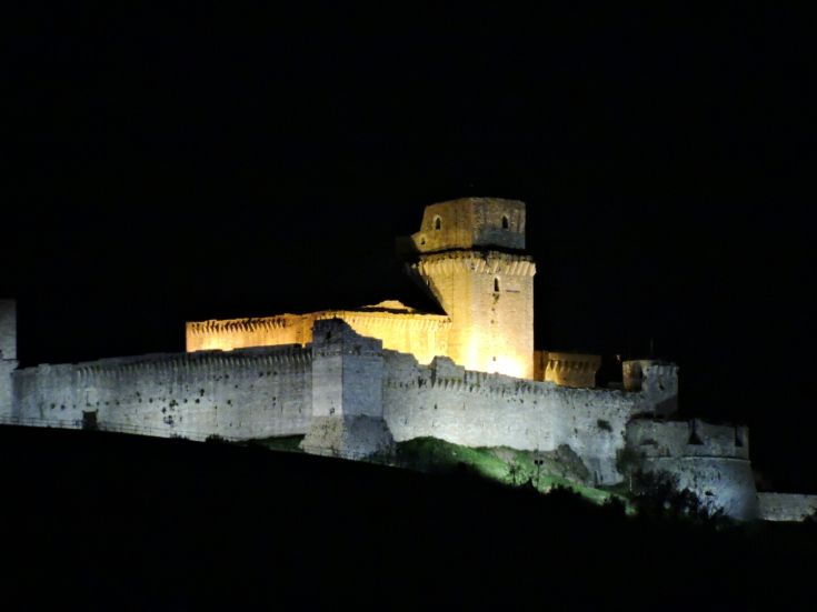 A nighttime view of a castle, softly illuminated, highlighting its architectural details.