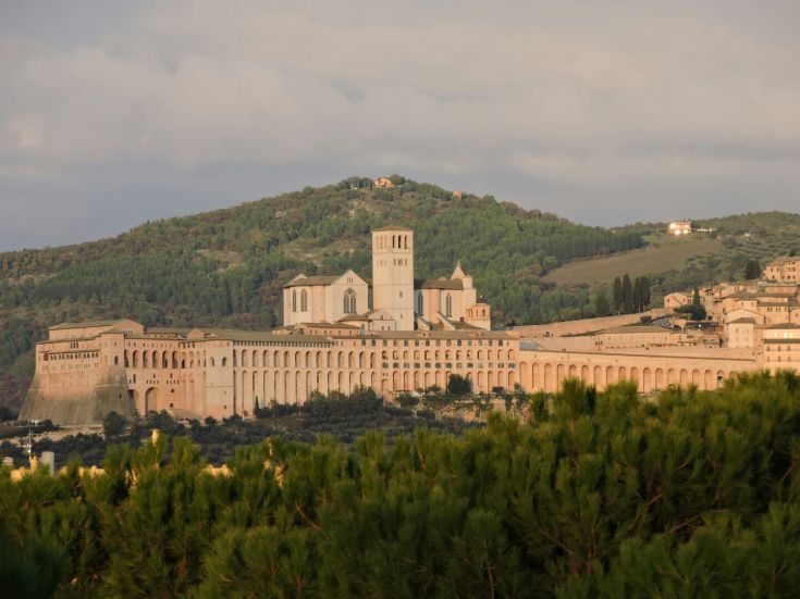 Basilica of San Francesco in Assisi, a significant religious structure surrounded by lush greenery.