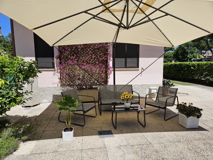 Outdoor space with sofas, umbrella, and plants, perfect for enjoying peaceful moments outside.