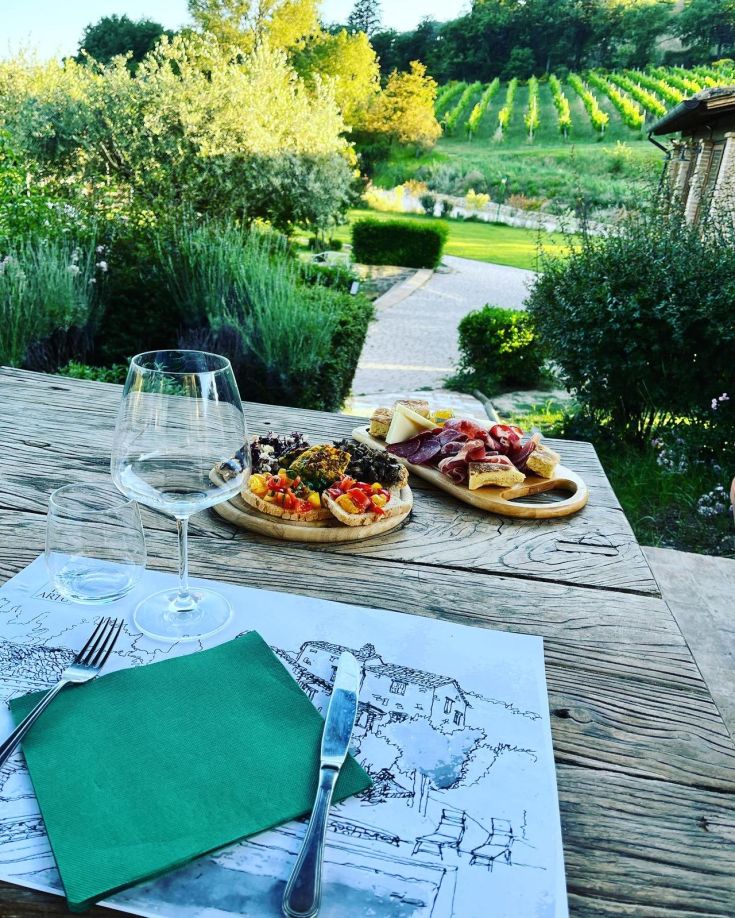 Aperitivo in vigna con un menù semplice sul tavolo e panorami delle vigne circostanti.