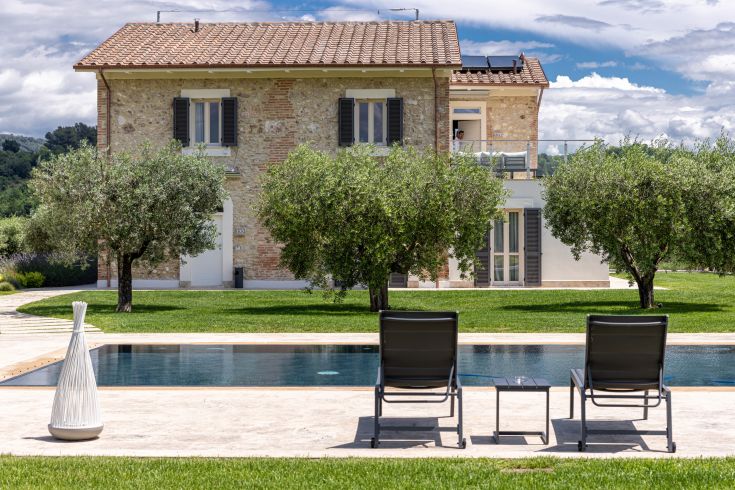 Villa mit Pool, umgeben von Olivenbäumen und sanften Hügeln, ein ruhiger Ort für einen entspannten Aufenthalt.