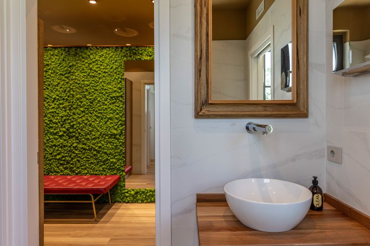 Modernes Bad mit zeitgemäßem Waschbecken und Spiegel. Grüner Wand mit natürlicher Oberfläche.