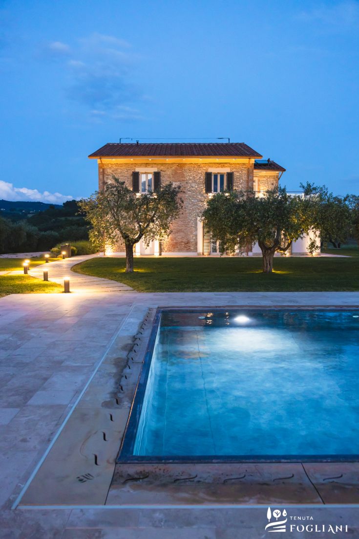 Eine Villa mit Swimmingpool in der umbrischen Landschaft, beleuchtet von der Abenddämmerung.