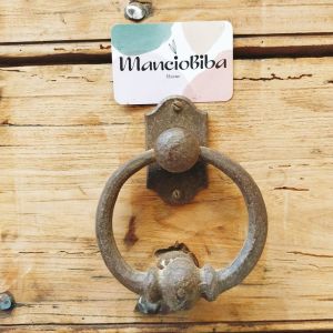 Un bouton de porte en fer forgé à côté d'une carte de visite de MancioBiba Home.