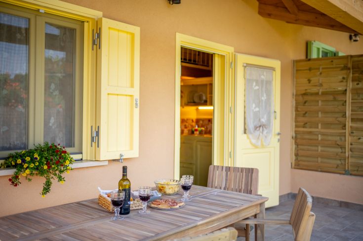 Une zone extérieure paisible avec une table, du vin et des collations, entourée de verdure.