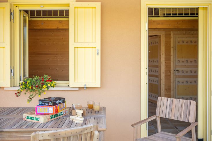 Une table en plein air entourée de jeux et de fleurs dans un environnement lumineux et serein.