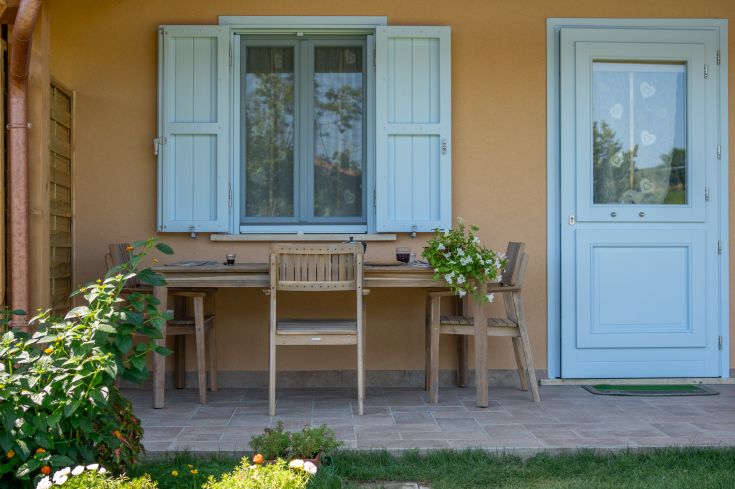 Un porche simple avec une table en bois et quelques plantes fleuries, idéal pour des moments de détente en plein air.
