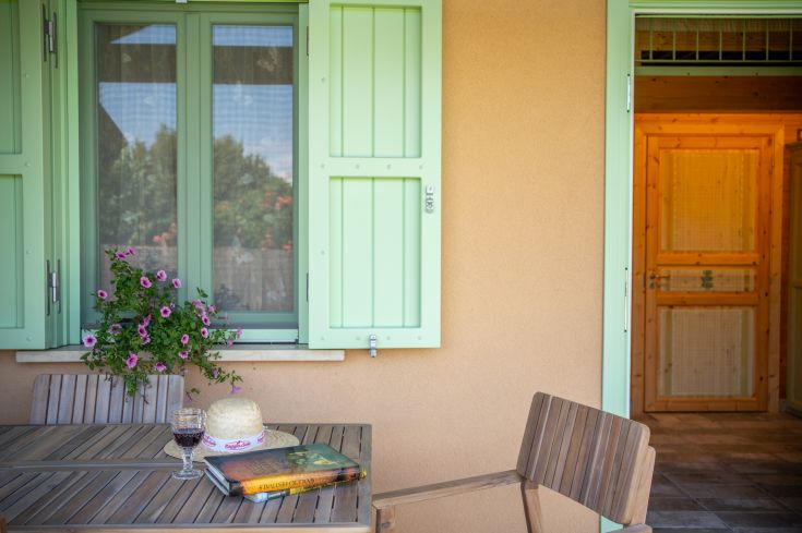 Un coin tranquille en plein air avec des fleurs, une bouteille de vin et des livres, idéal pour un moment de détente.