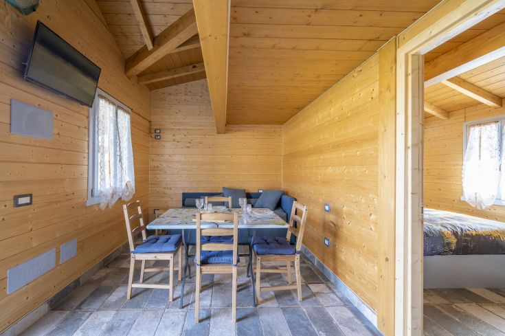 Une salle à manger en bois avec une table et une télévision, offrant une atmosphère chaleureuse et accueillante.