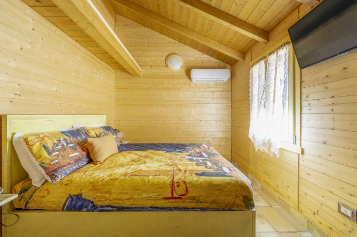 Chambre en bois avec un lit double et un décor simple, idéale pour un moment de tranquillité.