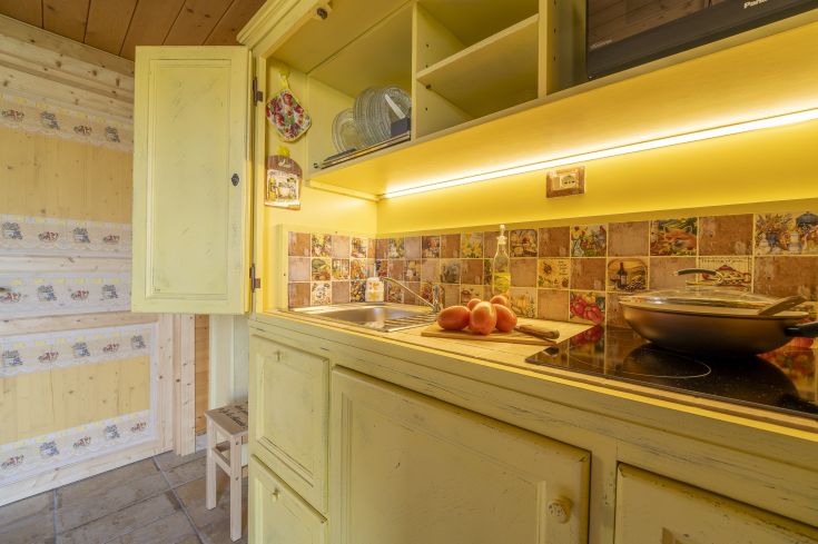 Cuisine simple avec des armoires jaunes et un sol carrelé, idéale pour les repas en famille.