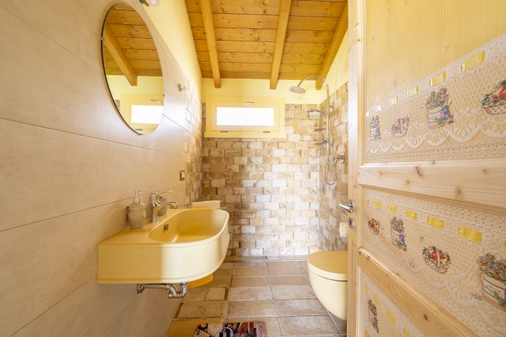Salle de bain lumineuse avec des accents jaunes et des matériaux naturels, idéale pour se détendre.