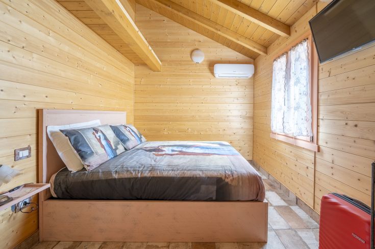 Chambre simple en bois avec un lit double, idéale pour des moments de détente.