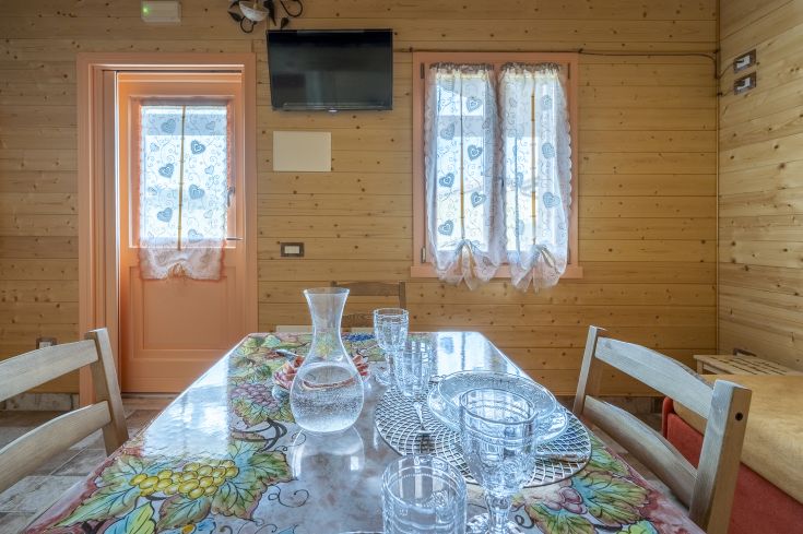 Intérieur confortable avec une table dressée, des murs en bois et de la lumière entrant par les fenêtres.
